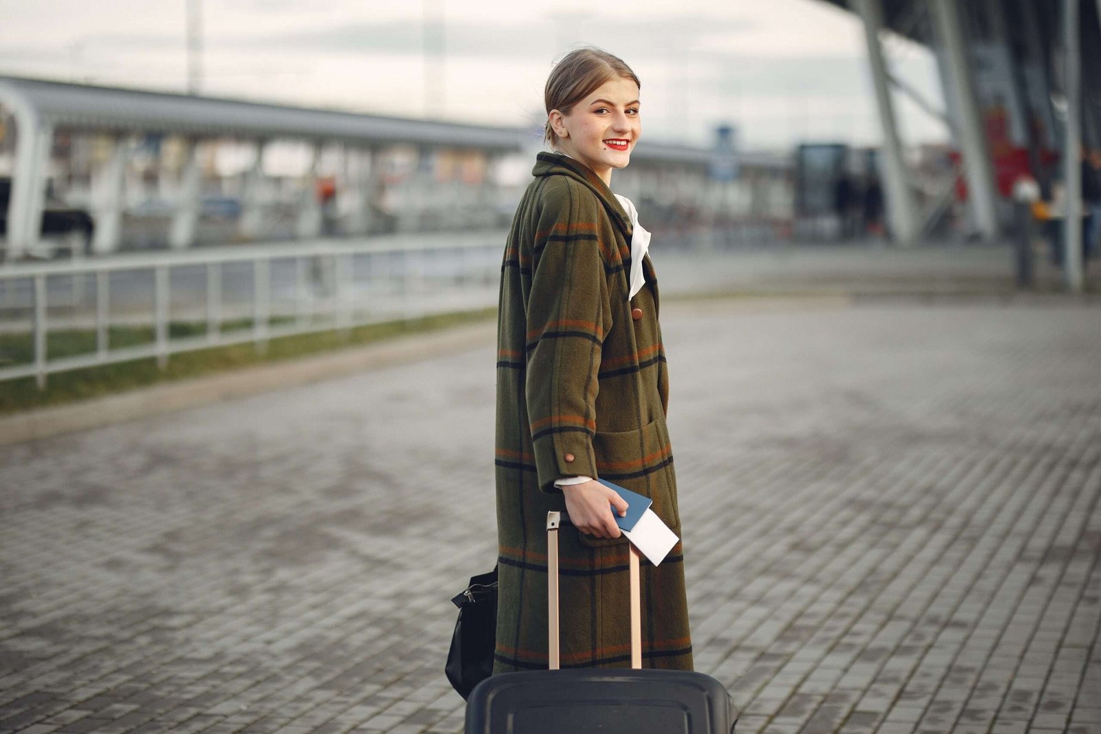 Photo by Gustavo Fring: https://www.pexels.com/photo/smiling-female-traveler-walking-with-suitcase-and-passport-near-train-station-3885530/